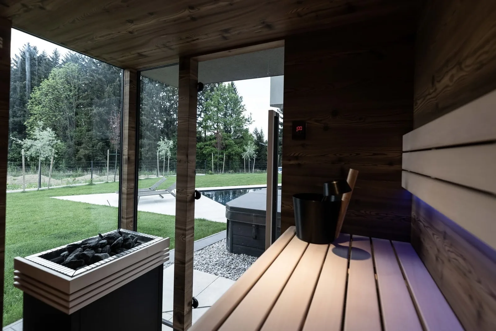 Gartensauna von innen mit Blick auf Wiese und Pool