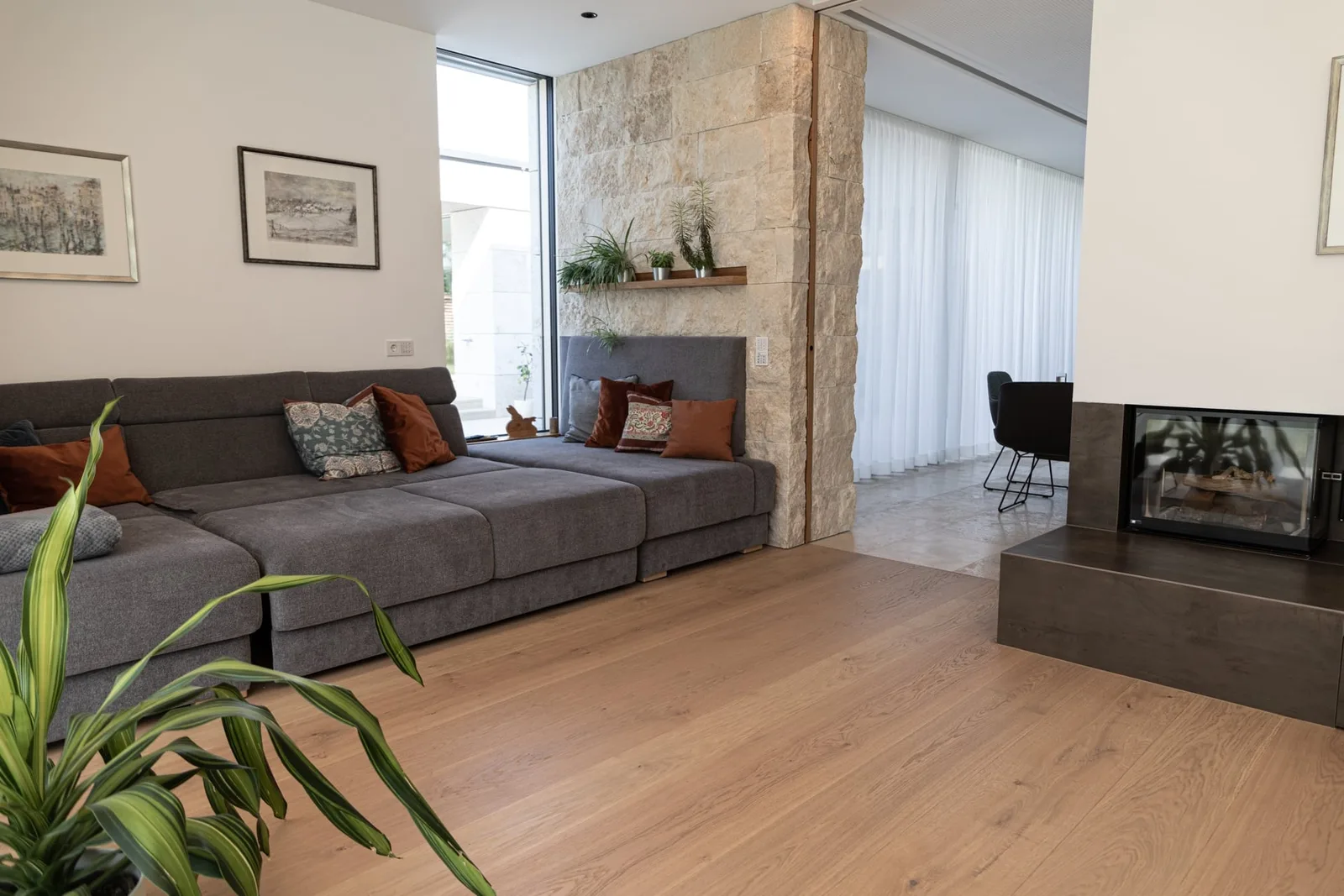 Wohnzimmer mit Kamin, Sofa und hellem Holzboden